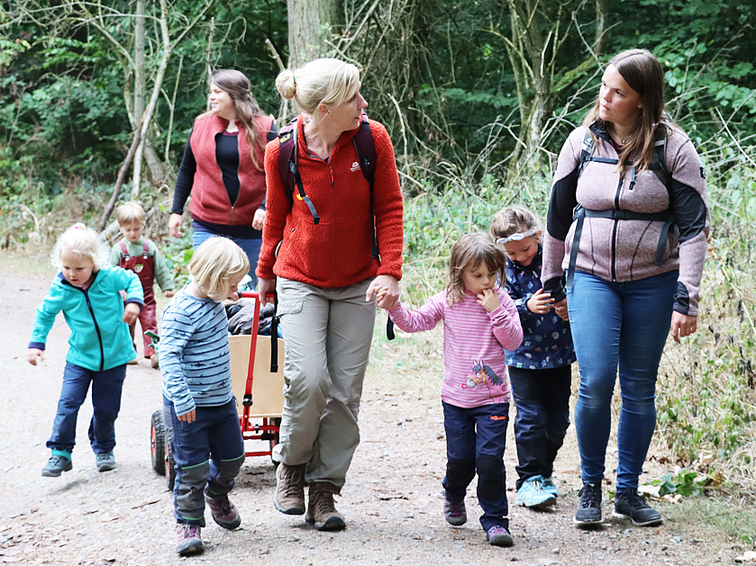 Erzieher und Kinder gehen im Wald spazieren