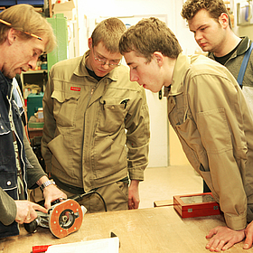 Mitarbeiter der Gerd-Halhbrock-Werkstatt erklärt einer Gruppe ein Gerät