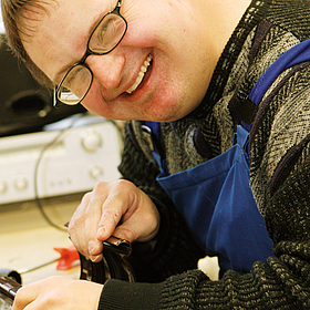 Mann lächelt und arbeitet in der Gerd-Halhbrock-Werkstatt