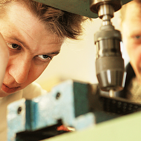 Detailaufnahme, wie ein ein Mitarbeiter der Gerd-Halhbrock-Werkstatt eine Maschine bedient