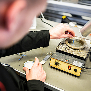 Nahaufnahme eines Mitarbeiters der Werkstatt Afferde bei der Arbeit im Bereich "Elektrotechnik"