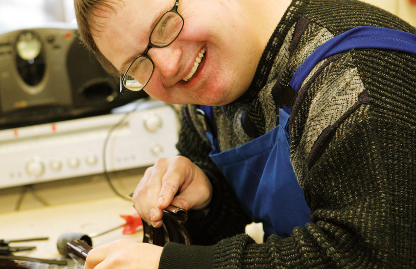 Mann lächelt und arbeitet in der Gerd-Halhbrock-Werkstatt