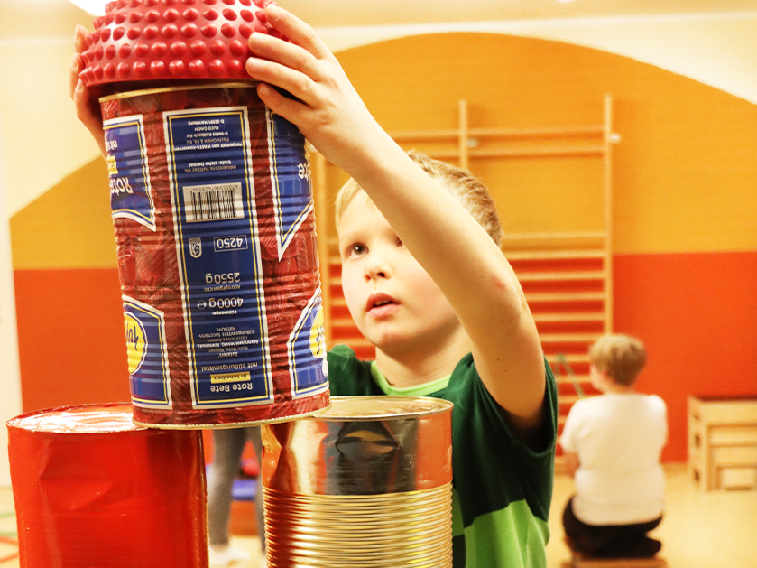 Junge stapelt Dosen zum einem Turm