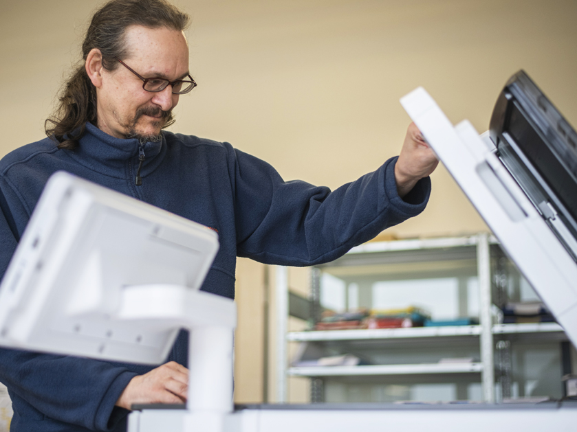 Mitarbeiter vom CopyShop am Kopierer