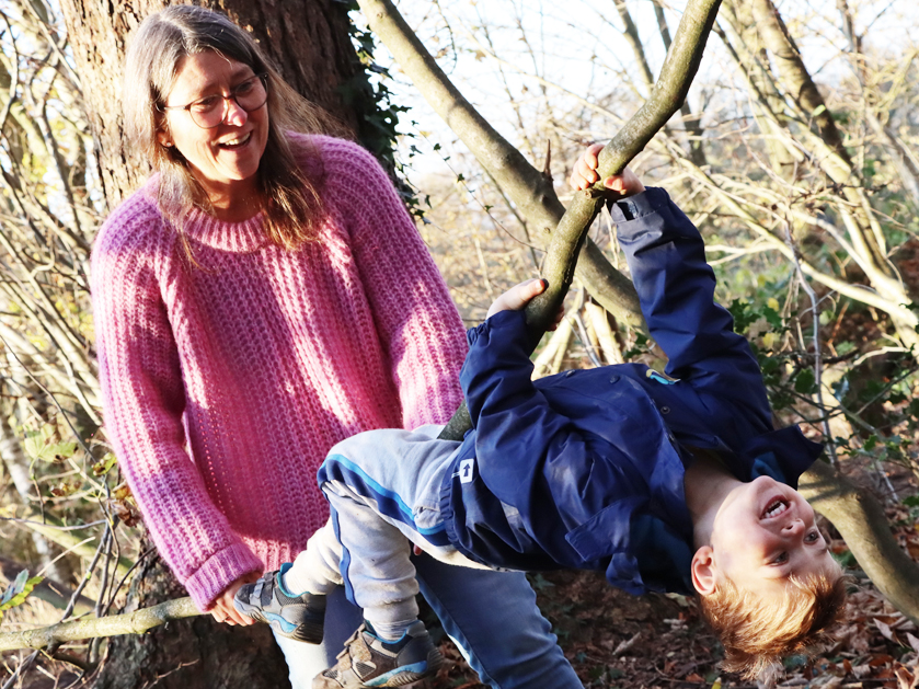 Frühförderin und Junge klettern im Wald