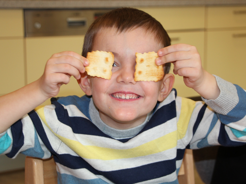 Junge hat Spaß und verdeckt seine Aufgen mit Crackern