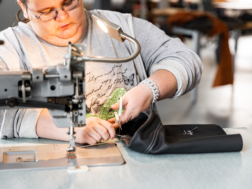 Mitarbeiterin bei m Nähen von Lederbeuteln