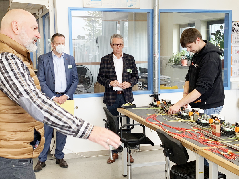 Mitarbeiter zeigt Besuchern die Elektromontage