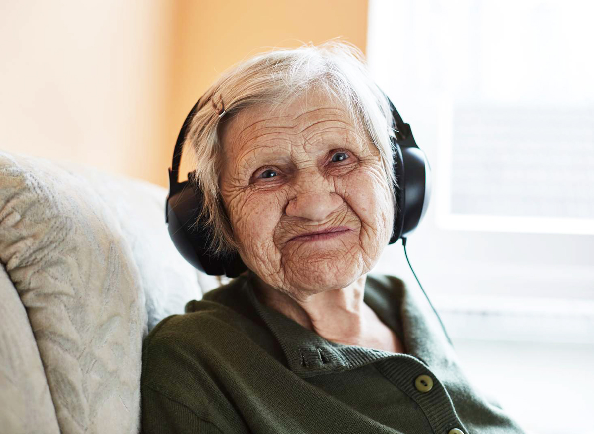 Seniorin hört Musik in Tagesbetreuung