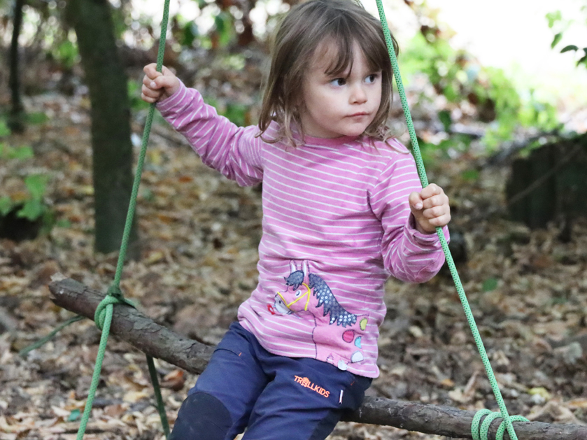Kindergartenkind beim Schaukeln im Wald
