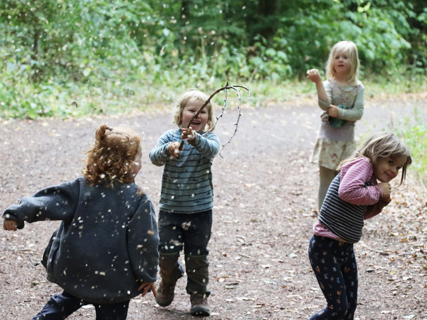 Kindergartenkinder bei Blätterschlacht im Wald