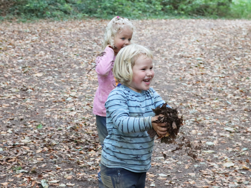 Kindergartenkinder bei Blätterschlacht im Wald